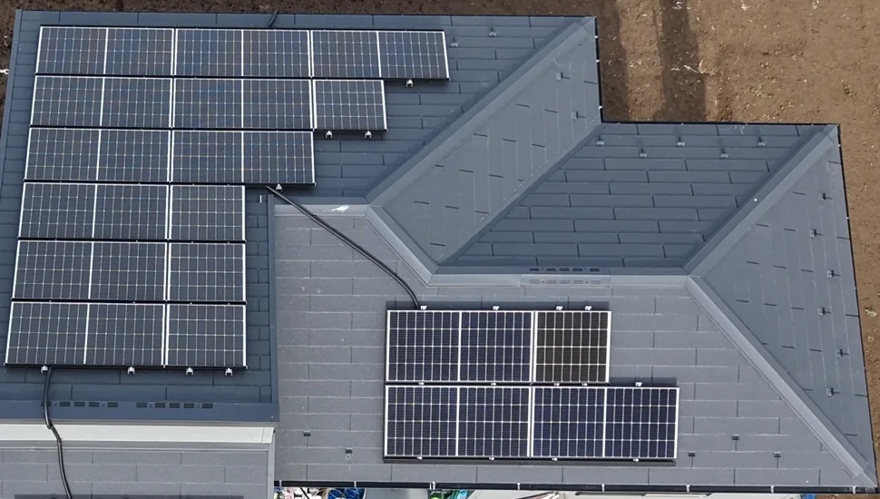 畑に囲まれた住宅の寄棟屋根とカーポートに設置した太陽光パネル